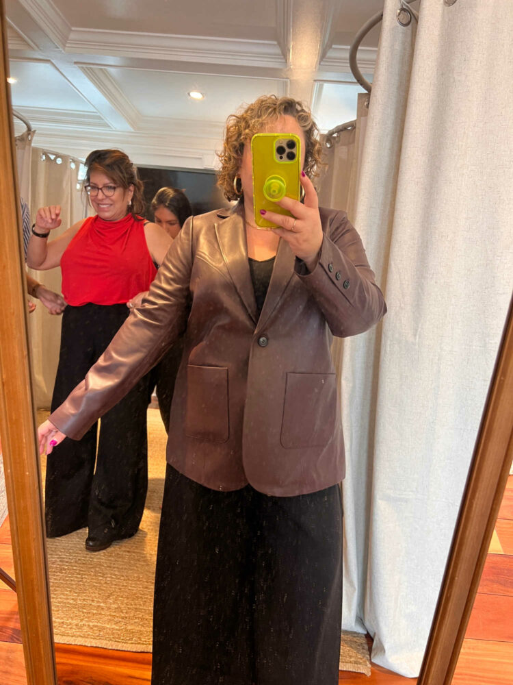 a woman trying on a leather blazer at a Universal Standard trunk show