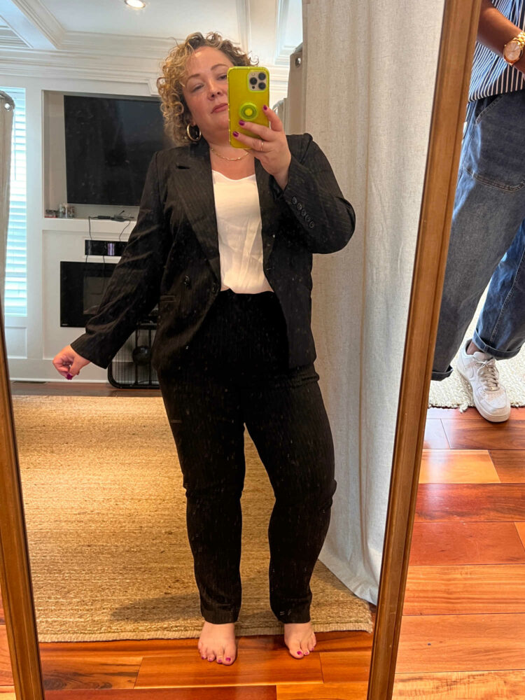 a woman trying on a Universal Standard pantsuit, taking a photo of her reflection in a mirror