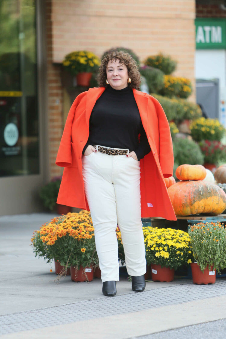 Alison Gary of Wardrobe Oxygen in ivory Talbots corduroy jeans with a black turtleneck and an orange boiled wool duster over her shoulders.