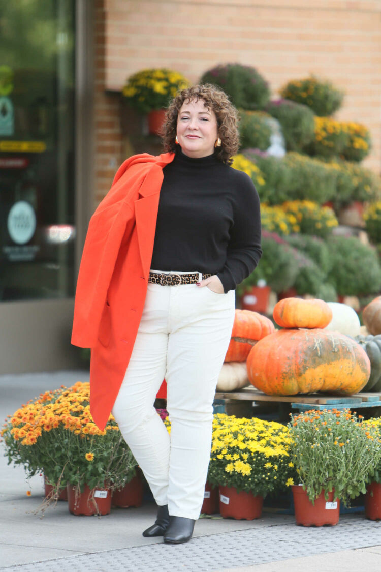 Alison Gary of Wardrobe Oxygen in Talbots stretch corduroy straight leg pants in ivory styled with a black turtleneck sweater, leopard calfhair belt, and orange wool duster.