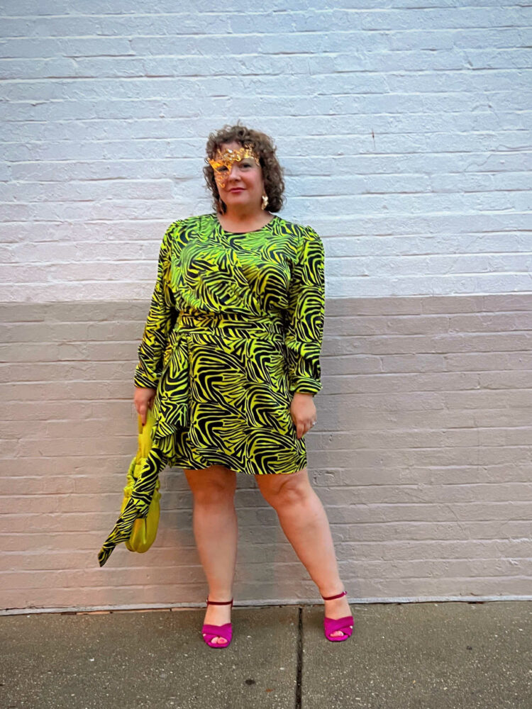 Alison in a lime green and black zebra print satin long-sleeved mini dress from Ronny Kobo with a lime green satin bag from GANNI and magenta suede heeled sandals. SHe is wearing a gold "Phantom of the Opera" half-mask as she attended a masquerade ball.
