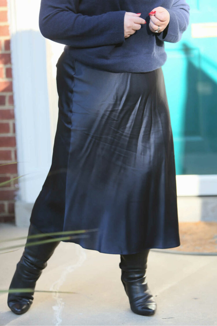 A photo of the Quince washable silk skirt on a 5'3" size 14 woman. It shows mild creasing on the silk from wear and sitting.