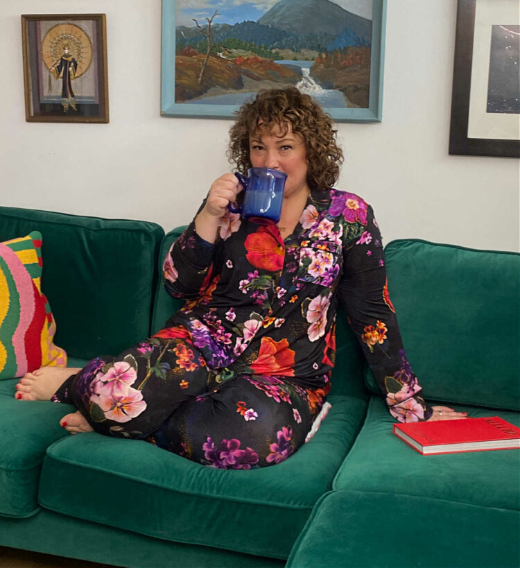 Alison of Wardrobe Oxygen wearing Soma Cool Nights pajamas while drinking coffee, curled up on a green velvet sofa from Albany Park