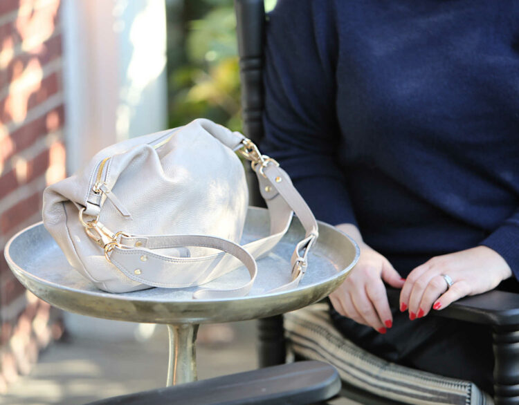 A closeup of the Quince  Italian Leather Convertible Crescent Shoulder Bag in Taupe after carrying for over a month. It still looks like new and has soft leather and shiny heavyweight gold hardware.