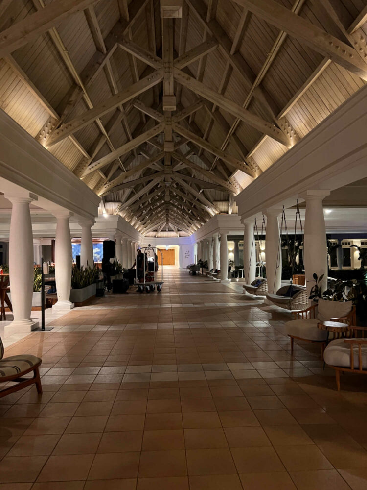 the entrance or foyer of the Curacao Marriott Beach Resort with a vaulted wood ceiling, tile floor, cream colored columns and artsy wood chairs for relaxing