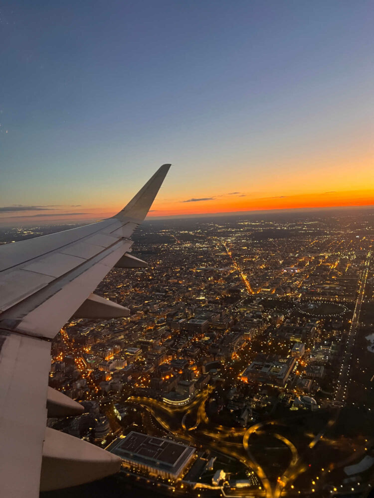 a plane wing over Washington DC as the sun rises