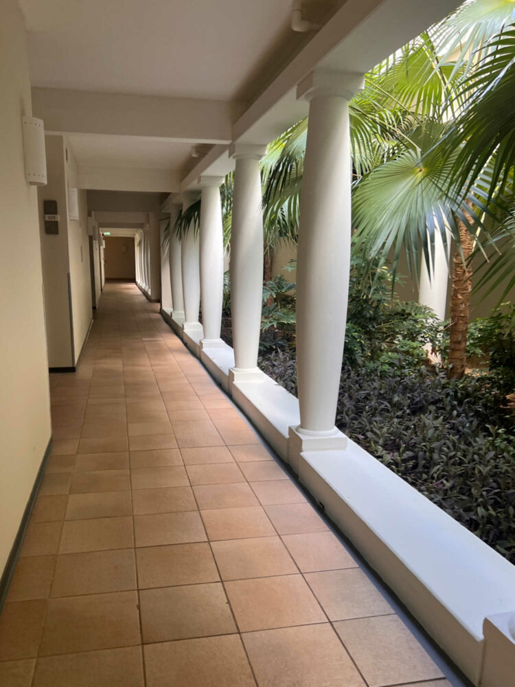 a hallway at the Curacao Marriott Beach Resort. Tiled and opening to courtyards of tropical greenery