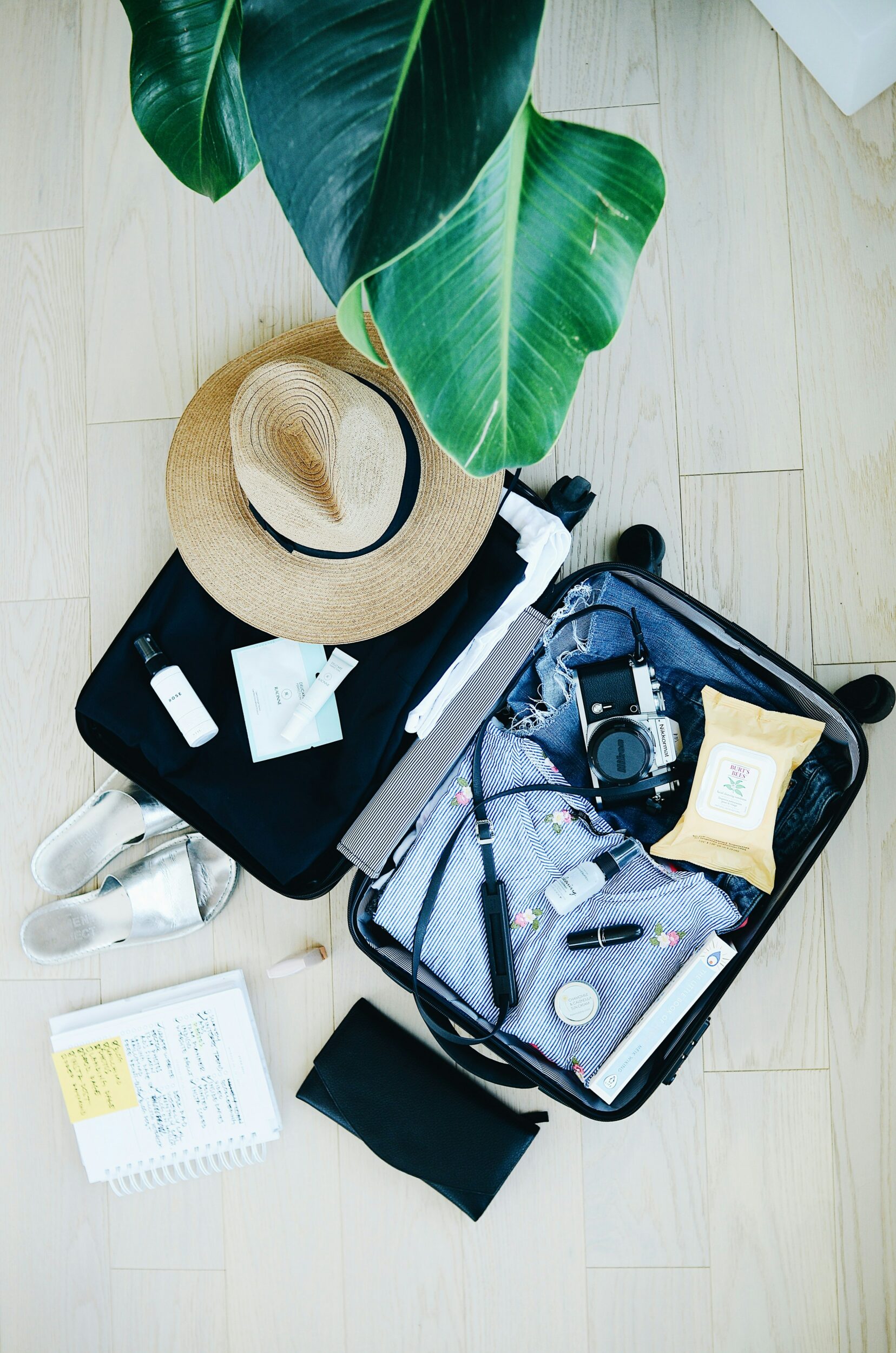 open suitcase packed with clothing and travel necessities with a hat sitting on top