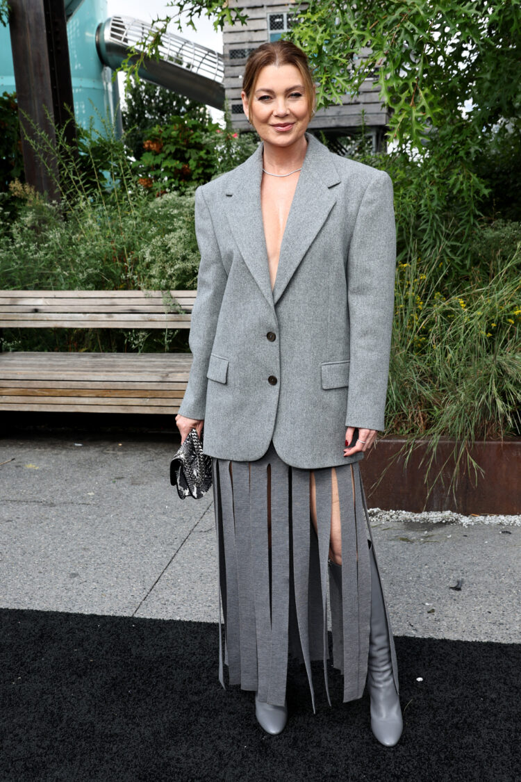 Ellen Pompeo at the Michael Kors show at NYFW February 2024 wearing an oversized gray blazer with gray fringe skirt and boots