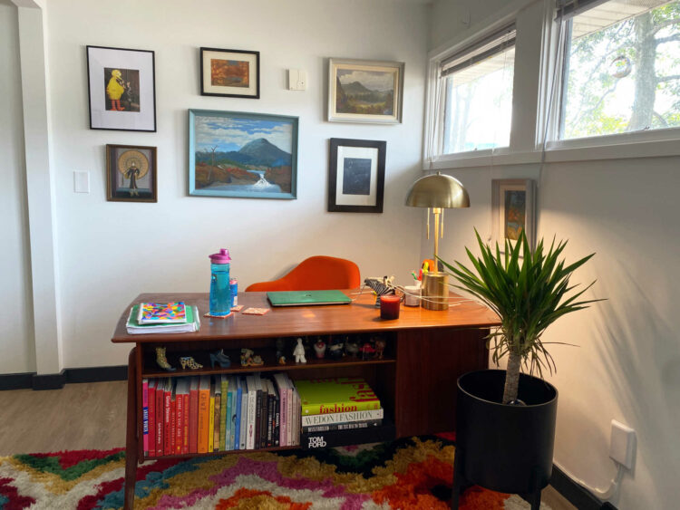 a gallery wall of art behind a mid century modern desk