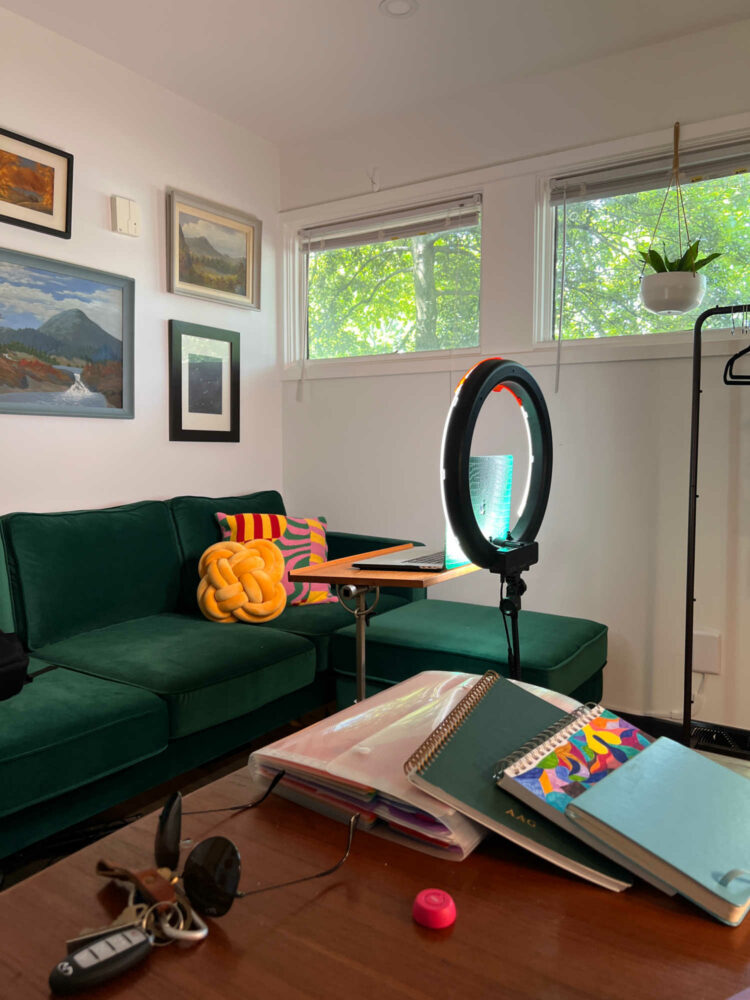 a green sofa with a ring light in front of it. Multiple pillows on the sofa