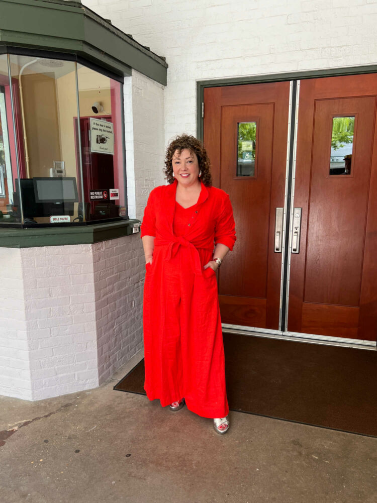 Alison Gary in the Universal Standard linen Promenade jumpsuit in orange with a matching linen tunic tied over it.