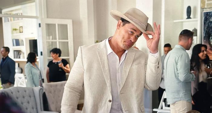 John Cena as Ricky Stanicky, in a linen suit, white shirt, and a safari hat