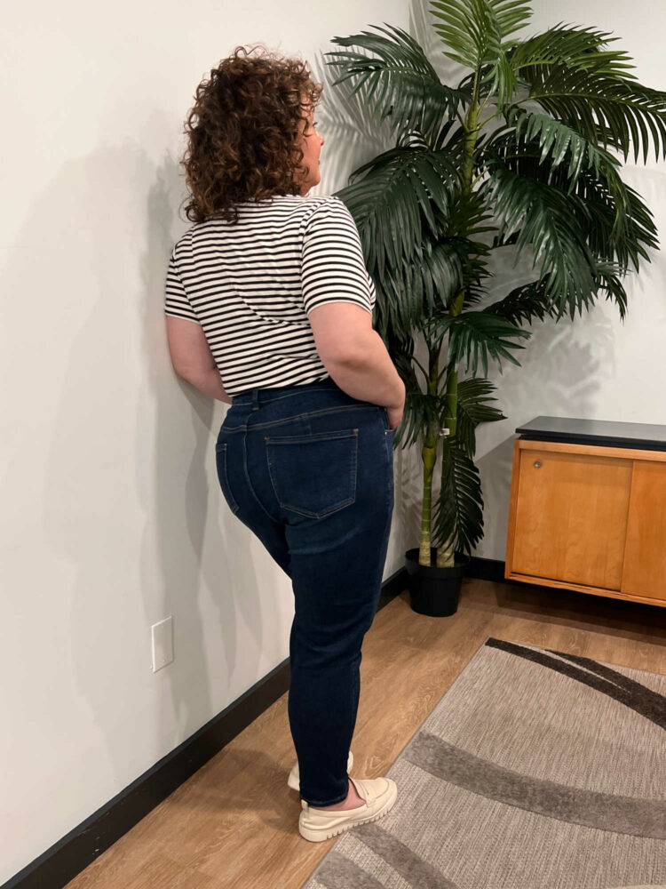 Alison facing away from the camera to show the back view fit of the Universal Standard Joni jeans
