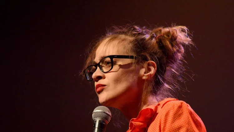 fiona apple in an orange blouse and glasses