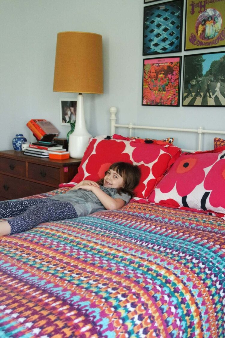 a bed covered with Marimekko sheets and a rainbow quilt