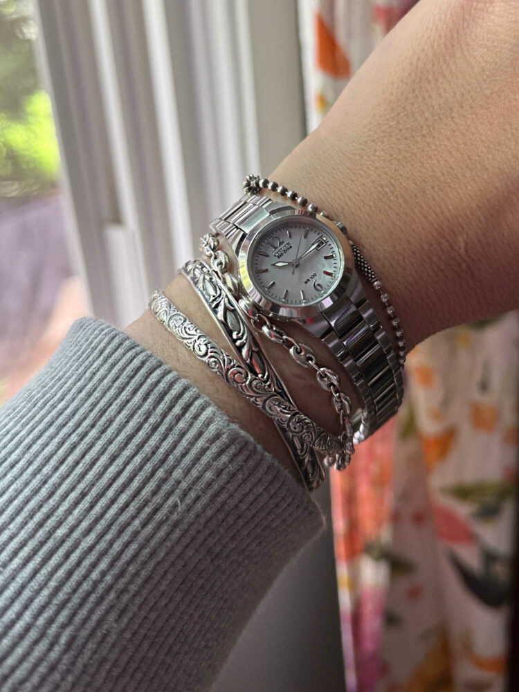 womans wrist with a silver Citizen Eco-Drive watch and four sterling silver bracelets
