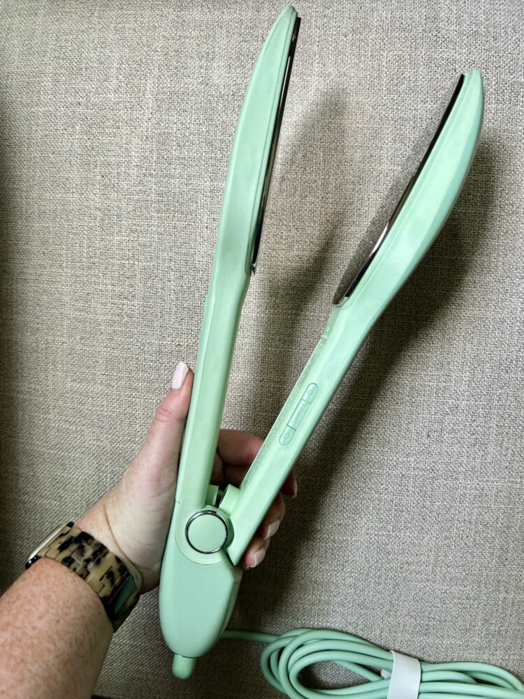 a hand holding a green Nori Press steam iron