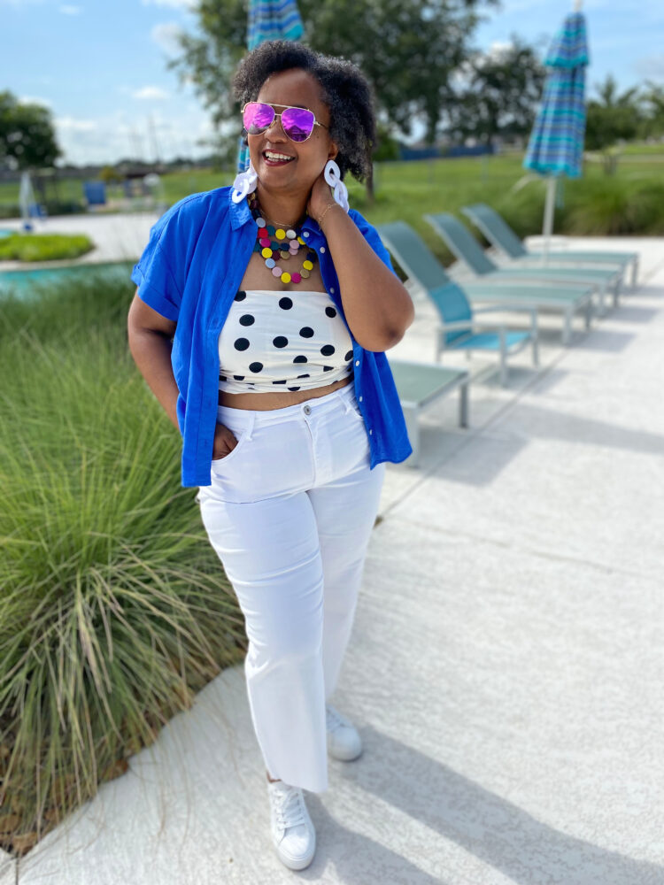 over 40 woman in a short sleeved blue shirt open over a polka dot tube top and white jeans