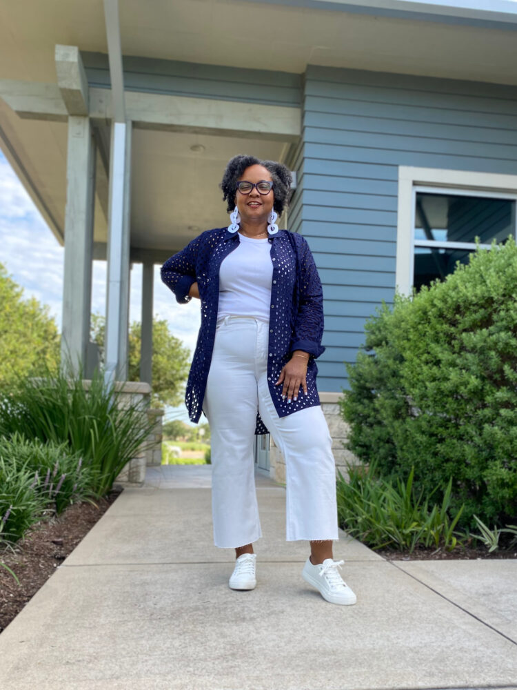 Over 40 woman wearing a navy eyelet tunic from J. Crew Factory styled with a white tank and white cropped wide leg jeans