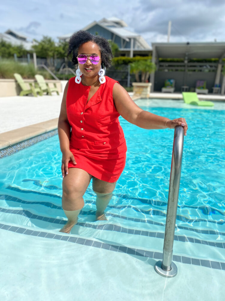 woman standing on the steps of a swimming pool wearing a J. Crew Factory linen mini dress in bright red