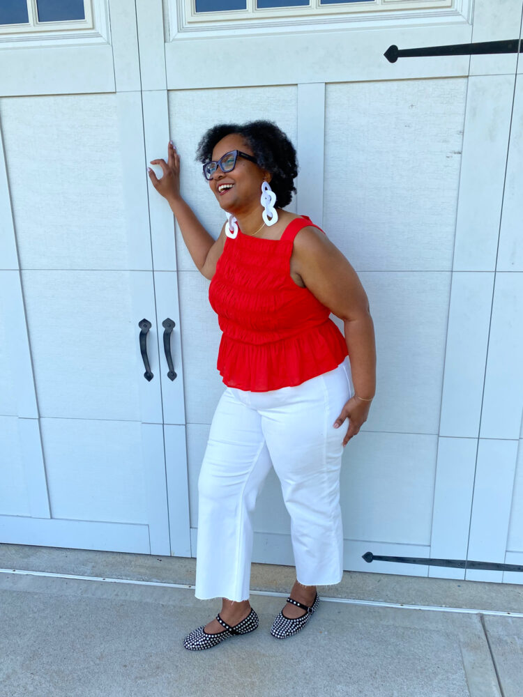 over 40 woman in a red smocked peplum summer top with white cropped wide leg jeans