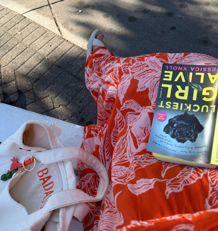 woman's lap holding the book luckiest girl alive