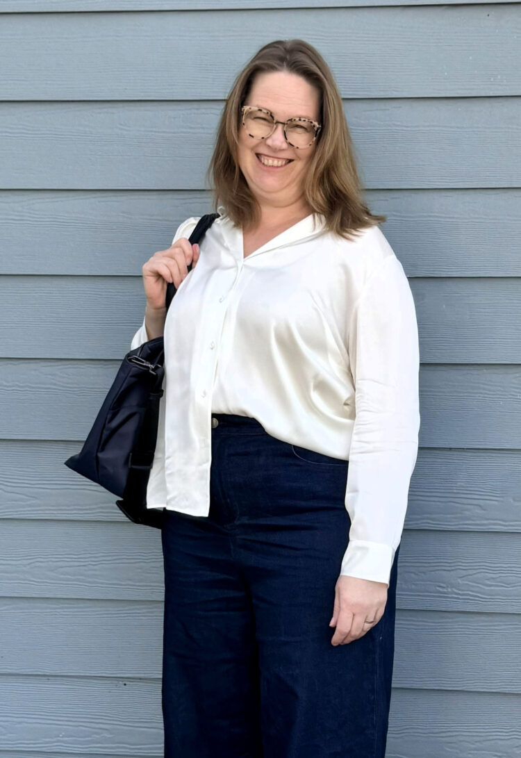 Quince Plus Size Clothing Review: An Honest Community Member Take 3 Tricia, a size 1X woman age 52, wearing the Quince Washable Stretch Silk Notch Collar Blouse in Ivory with wide-leg dark jeans and the Quince Voyage Nylon Travel Tote in Navy