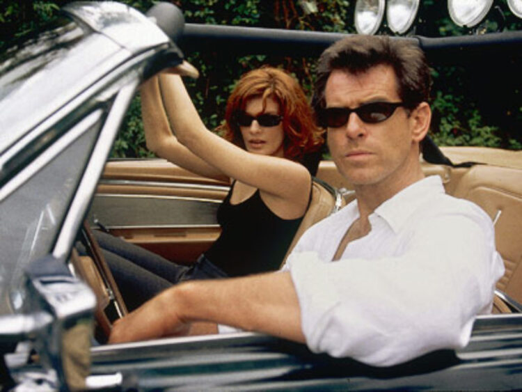 Weekend Reads for My Birthday Weekend 9 Rene Russo and Pierce Brosnan wearing sunglasses and sitting in a convertible in the movie The Thomas Crown Affair