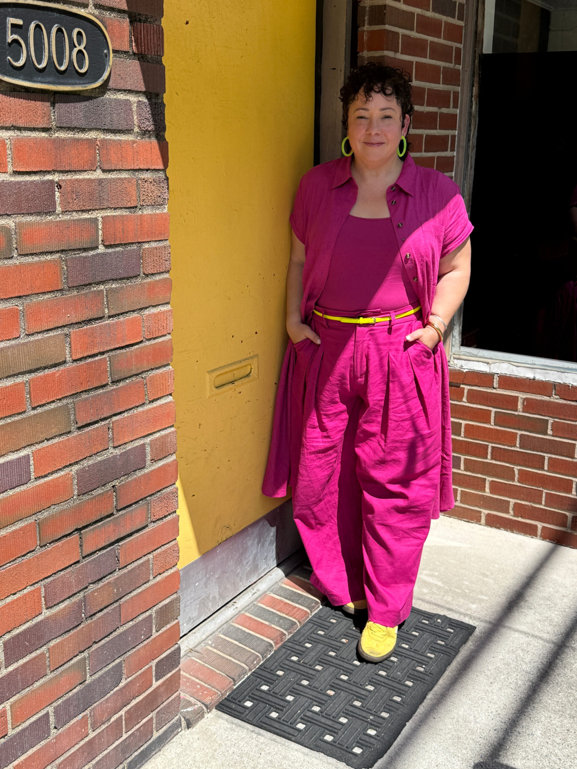 Alison in Universal Standard linen Dune shirtdress as a duster, Daisy tank, and Palais pants all in Hyper Pink with chartreuse Veja sneakers and a chartreuse skinny belt
