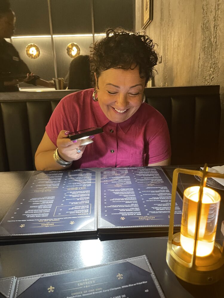 What I Wore Recently: August 2026 2 alison at a restaurant trying to read the menu with her phone flashlight since it was so dimly lit. She is laughing while wearing a Universal Standard stretch linen shirtdress